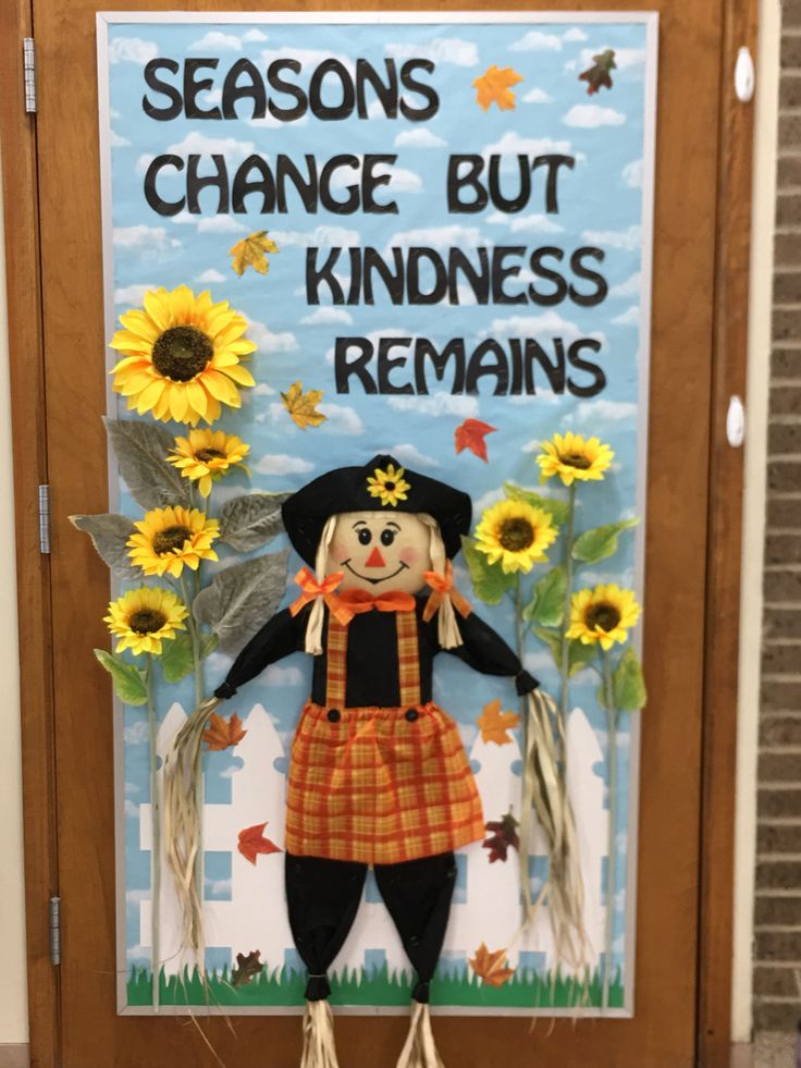 a scarecrow is standing in front of a sign that says, seasons change but kindness remains