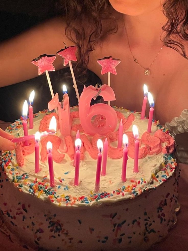 a woman sitting in front of a birthday cake with candles on it and the number sixty