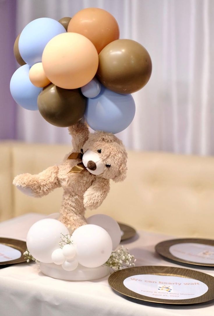 a teddy bear holding onto balloons on top of a table