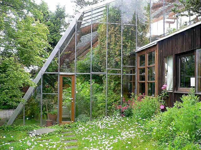 the house is made out of glass and has plants growing in it, along with flowers