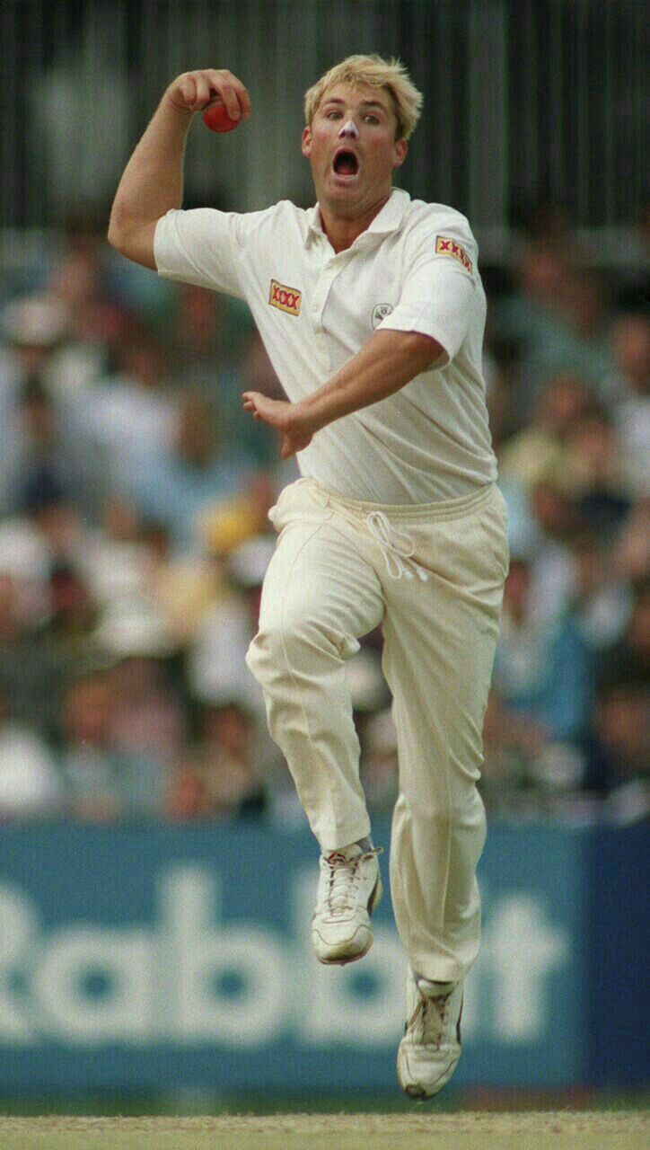 a man with his arms in the air as he runs to catch a cricket ball