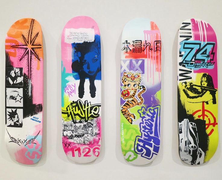 four skateboards with different designs on them are lined up in a row and one is upside down