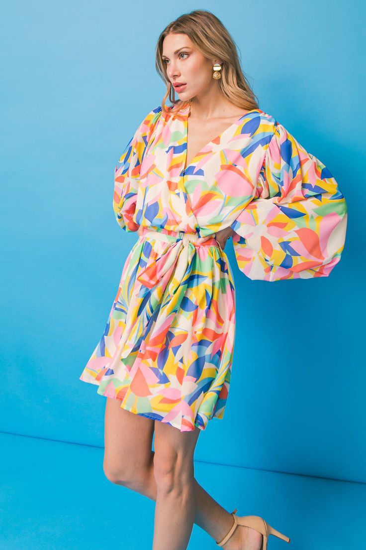 A printed woven mini dress featuring surplice neckline, long sleeve with smocked cuff, elasticized waist with self sash tie, and ruffled hemline Details Self: 100% Polyester Lining: 100% Polyester Size & Fit - Model is 5`8" And Wearing Size Small - Measurements Taken From Size Small - Approx. Length: 34" Chic V-neck Wrap Dress For Day Out, Chic Multicolor Mini Dress For Date Night, Flirty Mini Dress With Surplice Neckline For Summer, Flirty Multicolor Mini Dress, Chic Multicolor Mini Dress, Multicolor Flirty Dress For Brunch, Chic Multicolor V-neck Dress, Chic Multicolor V-neck Midi Dress, Chic Fitted Multicolor V-neck Dress