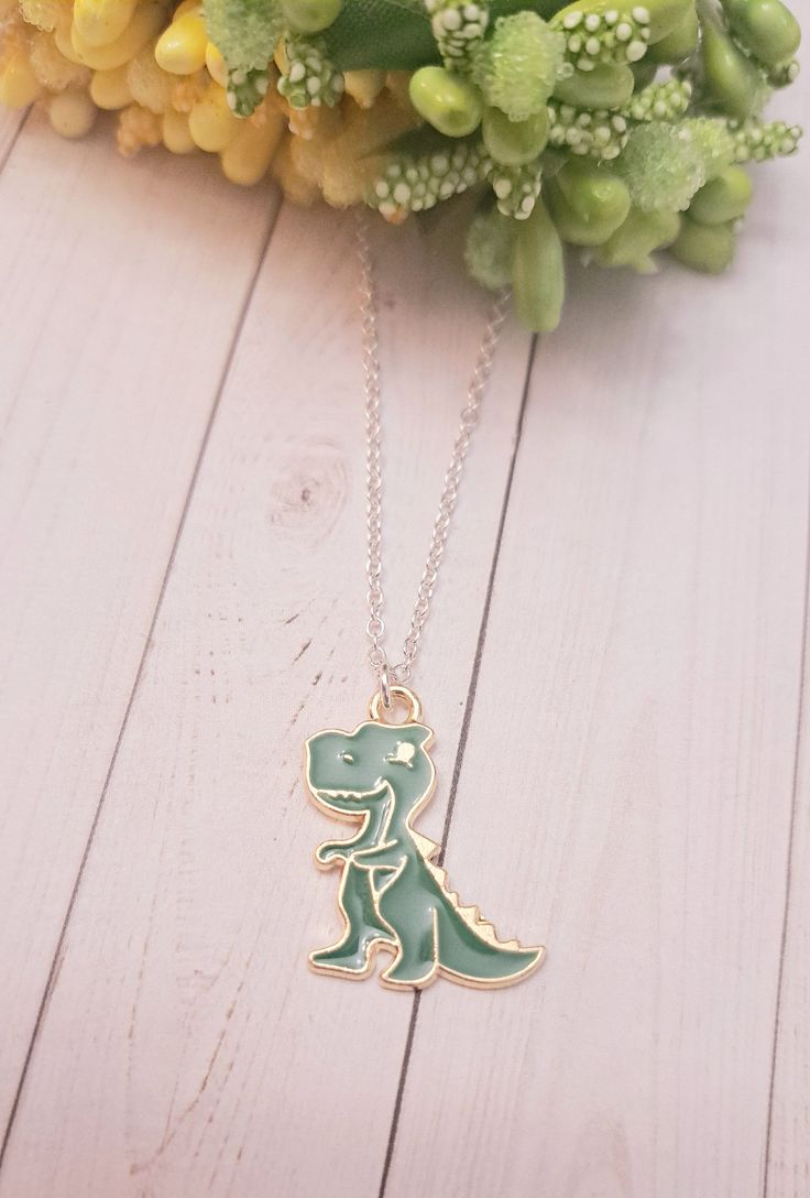 This cool dinosaur Charm Necklace is the perfect gift for someone special!  The charm is made of high-quality gold. This makes an excellent gift for yourself or your friends and family members who loves to collect Dinosaur jewelry. Product Details: Material: Sterling silver plated necklace Chain Length: 18 Inches (Can be made in different lengths) Charms: Dinosaur Charm. Please reach out to me  You can get these personalized necklaces in any length, so please contact me via Etsy Conversations if you need any size. This minimalist and dainty necklace is made with a high-quality material that is eco-friendly, durable, and anti-inflammatory. It won't leave your skin green due to marks. Moreover, the weight of the necklace is quite appropriate, and they come with a Lobster Clasp to provide you Personalized Green Jewelry For Best Friend Gift, Novelty Charm Necklaces For Gifts, Themed Necklace With Lobster Clasp As Gift, Novelty Jewelry With Lobster Clasp For Gift, Nickel-free Novelty Charm Necklace For Gift, Gold Novelty Charm Necklaces For Gifts, Gold Novelty Charm Necklace For Gifts, Novelty Necklace With Lobster Clasp For Gift, Green Novelty Jewelry For Birthday