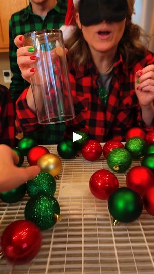 three people wearing christmas hats around a table with balls and ornaments on the counter top