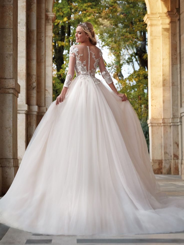 a woman in a wedding dress is standing on the stone walkway with her back to the camera