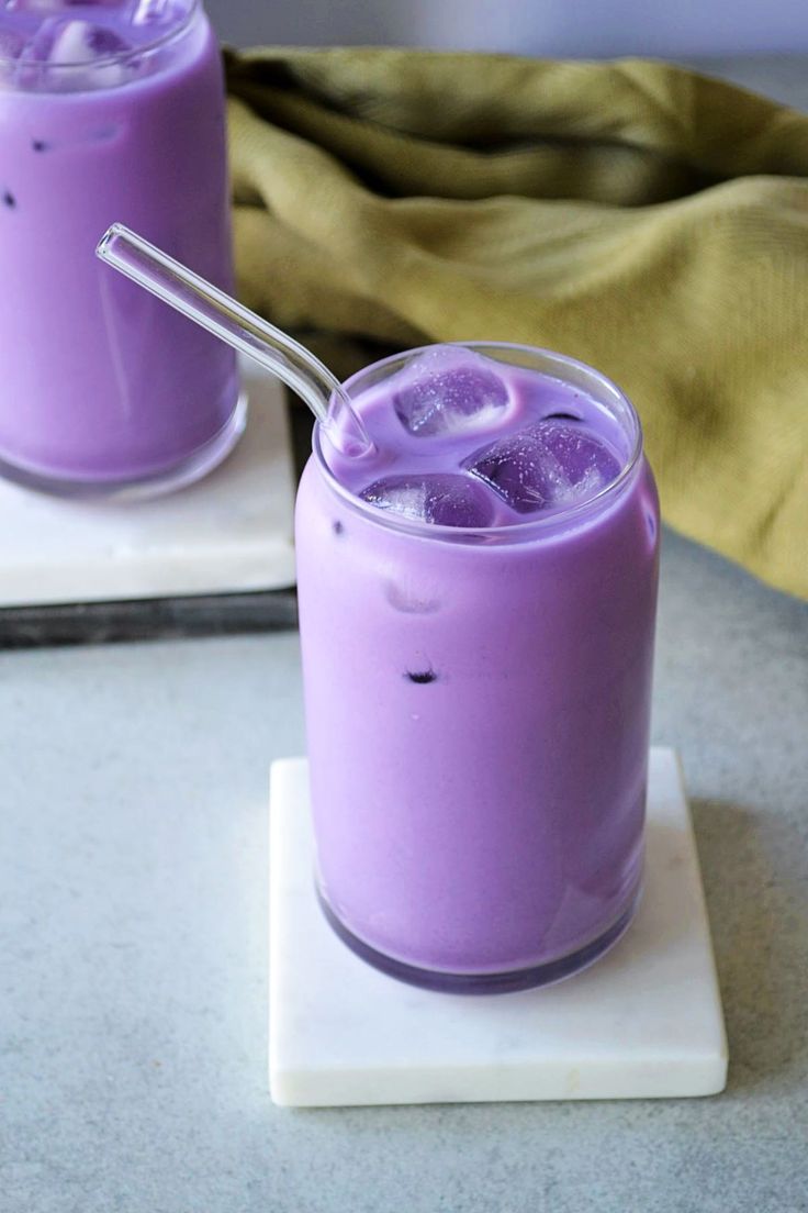 two glasses filled with purple liquid sitting on top of a white tray next to each other