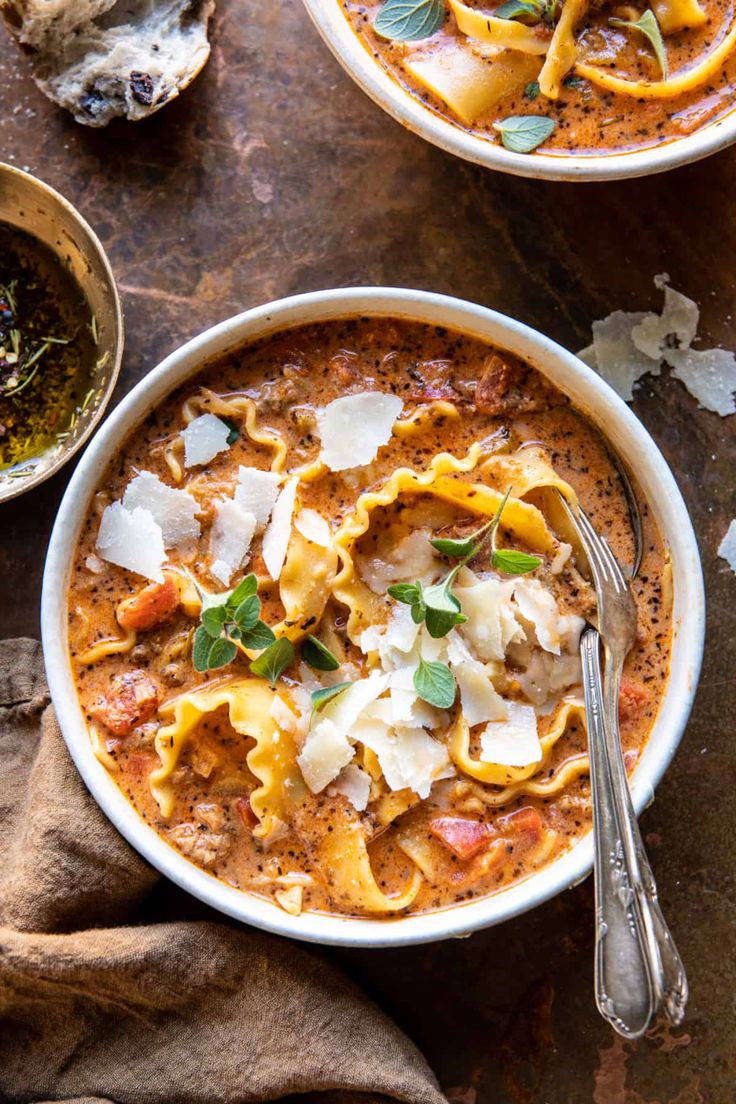 a white bowl filled with pasta and cheese on top of a wooden table next to a spoon