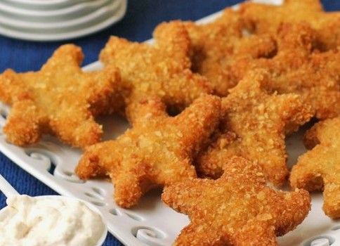 some fried food is on a white plate and blue table cloth next to plates with sauces