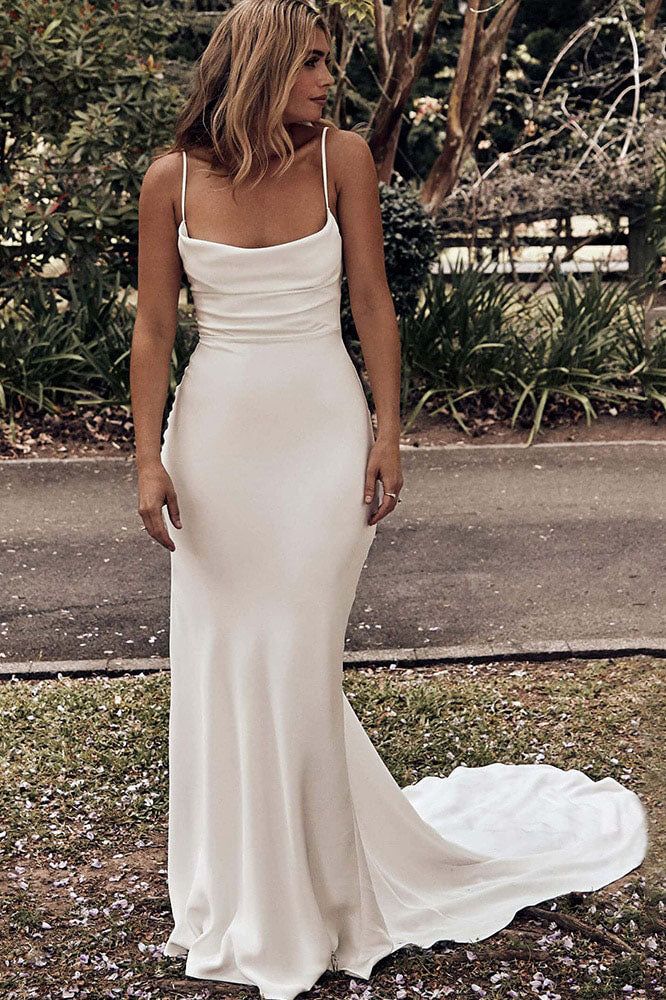 a woman wearing a white dress standing in the grass with her back to the camera