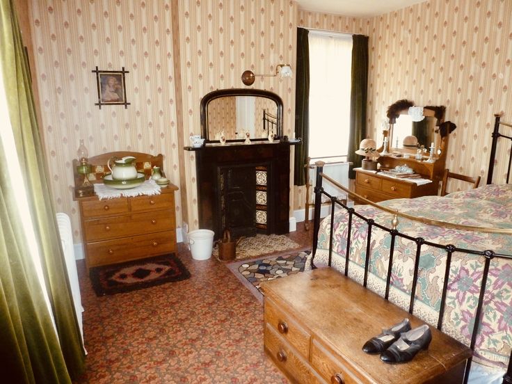 an old fashioned bedroom with floral wallpaper and antique furniture, including a large bed