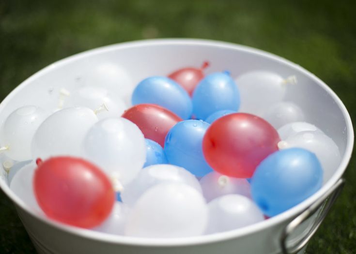 a bucket filled with red, white and blue balloons