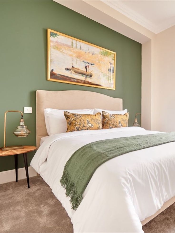 a bedroom with green walls and white bedding in the corner, along with a painting on the wall