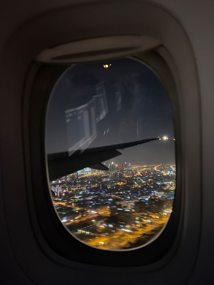 an airplane window looking out at the city lights