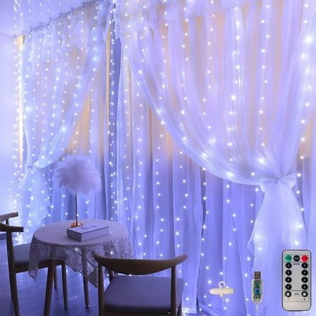 a living room with white lights on the curtains and a table in front of it