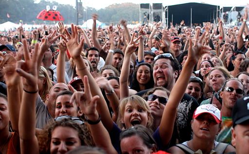 a large group of people standing in front of each other with their hands up to the sky