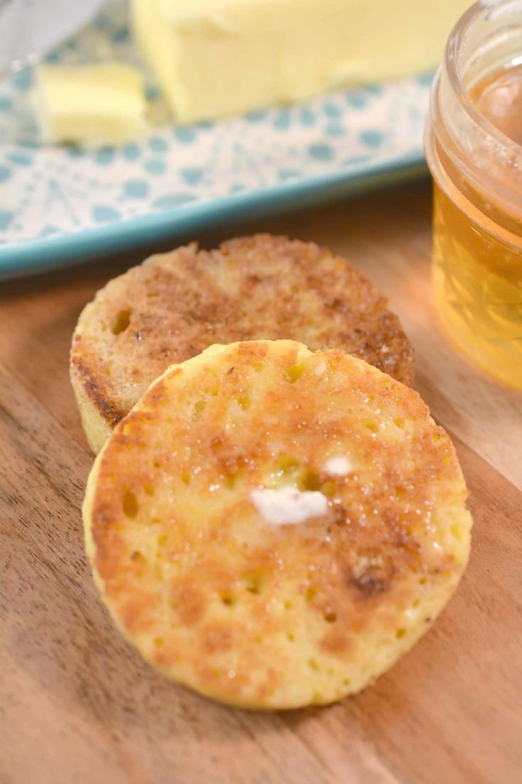 some food is sitting on a wooden table next to a jar of honey and butter