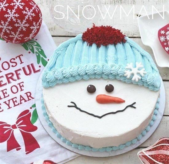 a snowman cake sitting on top of a wooden table next to other decorations and decorating items