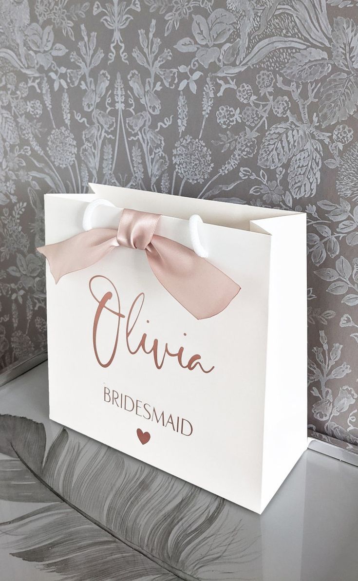 a bridesmaid gift bag with a pink bow on the front and brown lettering