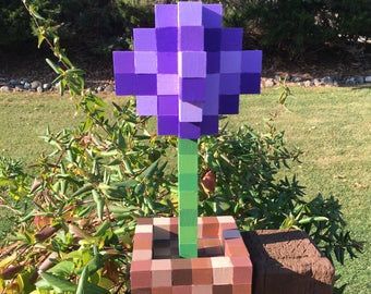 a purple flower sitting on top of a brick planter