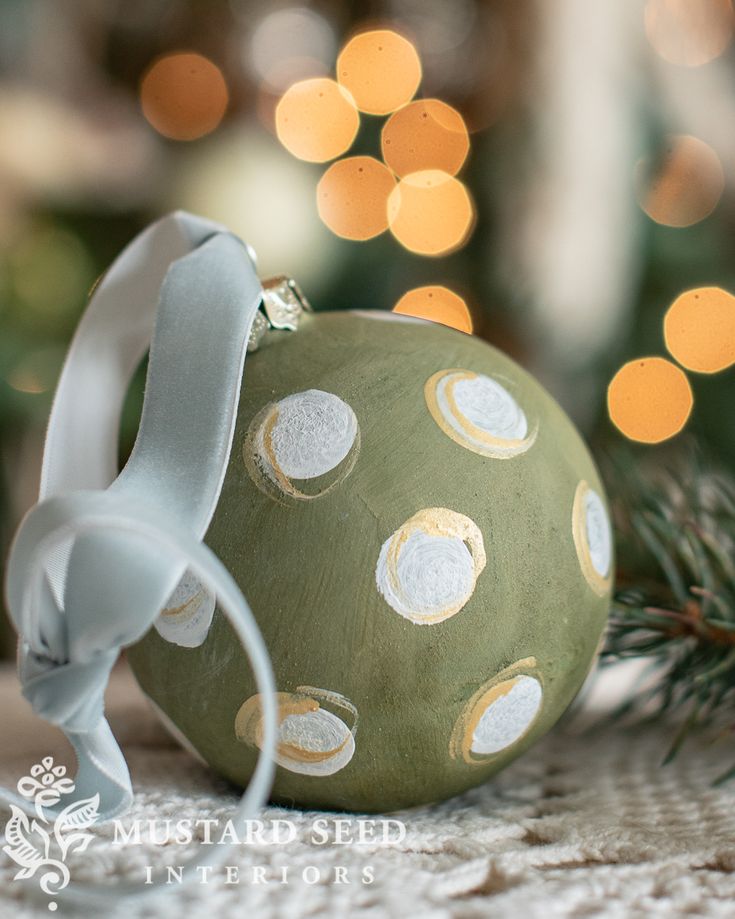 a green ornament with white polka dots on it sitting next to a christmas tree