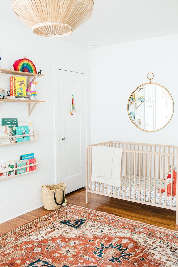 a baby's room with a crib, bookshelf and rug on the floor