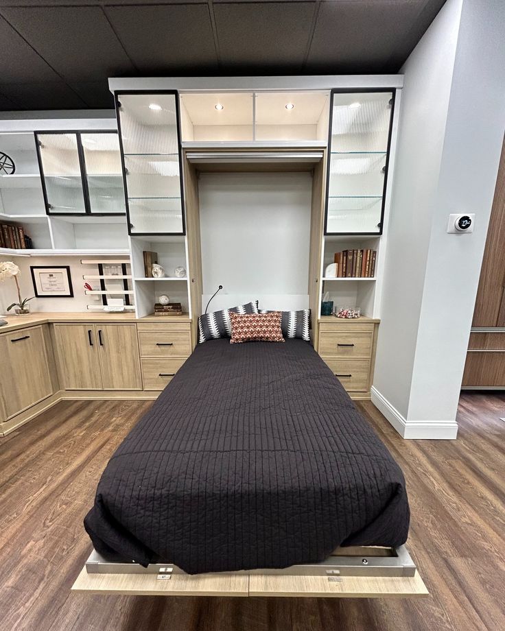 a bed sitting on top of a wooden floor next to a book shelf filled with books