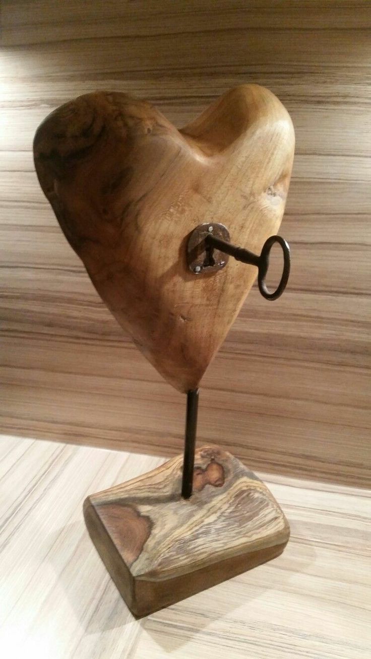 a wooden sculpture with a key in the shape of a heart on it's stand