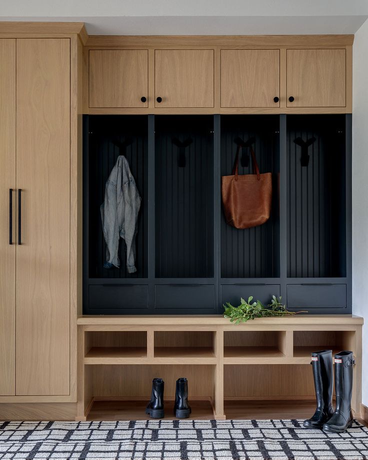 a wooden bench sitting in the middle of a room next to a coat rack and boots