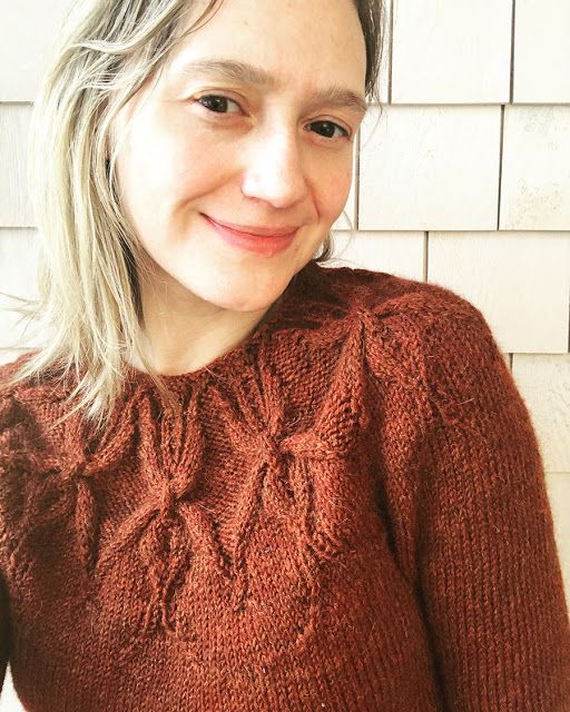 a woman with blonde hair wearing a brown sweater