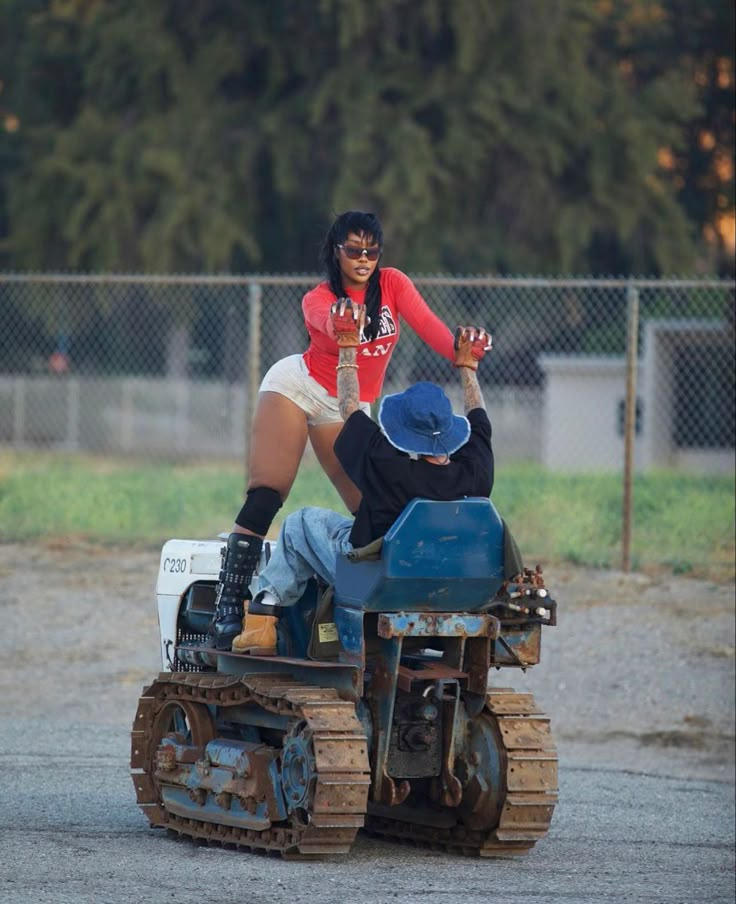 a woman in red shirt and white skirt riding on top of a small vehicle with man