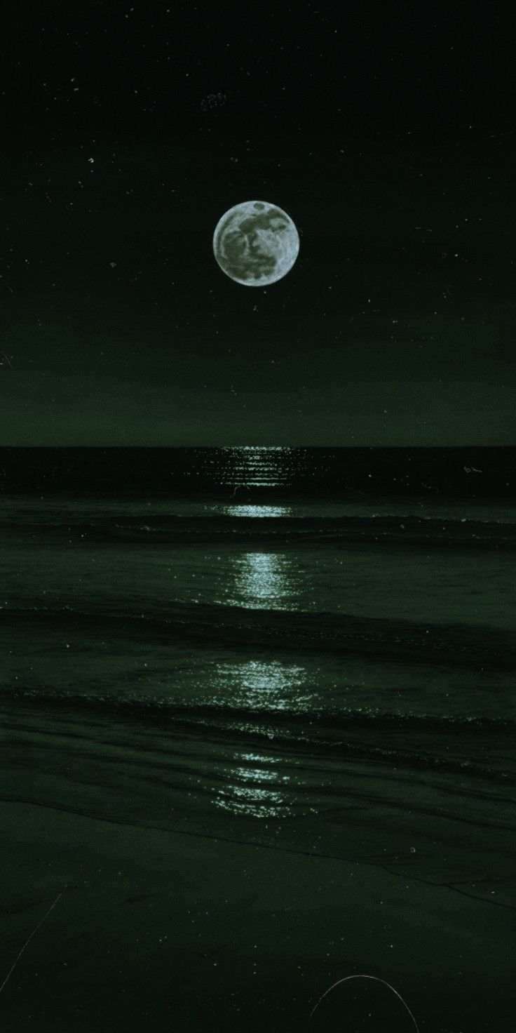 the moon is shining over the ocean at night