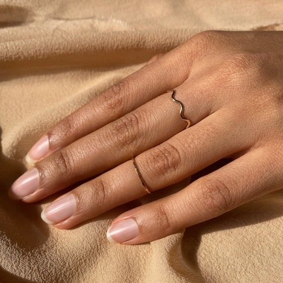 a woman's hand with a ring on her finger and the other hand is laying down