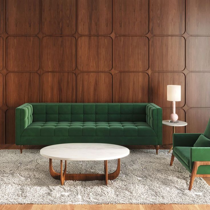 a living room with two green couches and a white coffee table in front of a wooden paneled wall