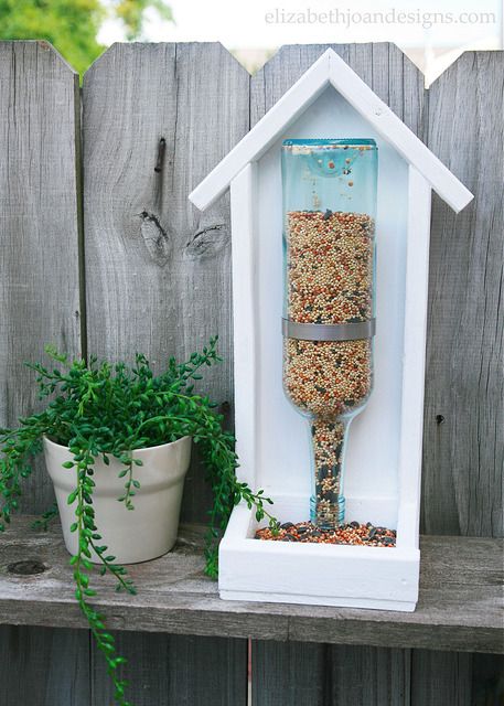 a bird feeder is on top of a wooden fence next to a potted plant