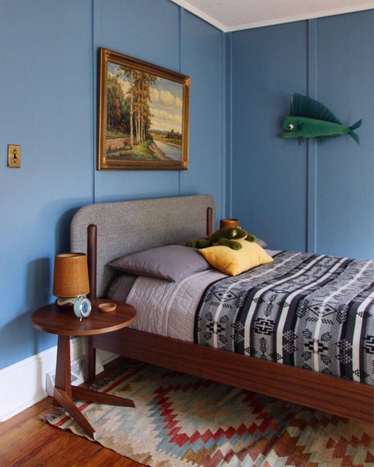 a bed room with a neatly made bed and a painting on the wall