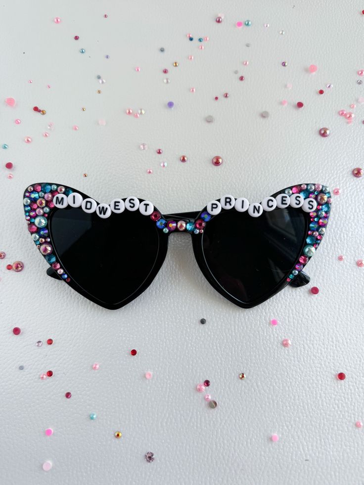 a pair of black sunglasses with pink, blue and white crystals on the top of them