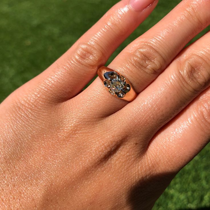 a person's hand with a ring on it and grass in the back ground