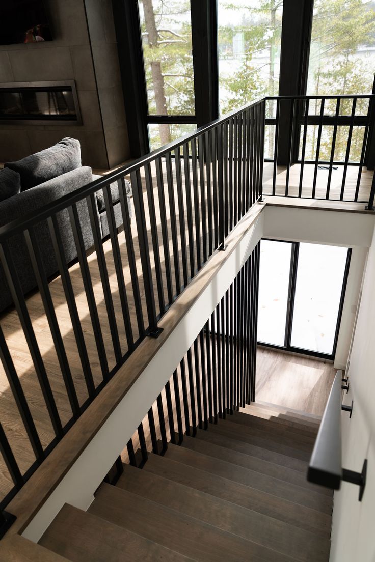 the stairs lead up to an open floor plan with glass doors and black railings