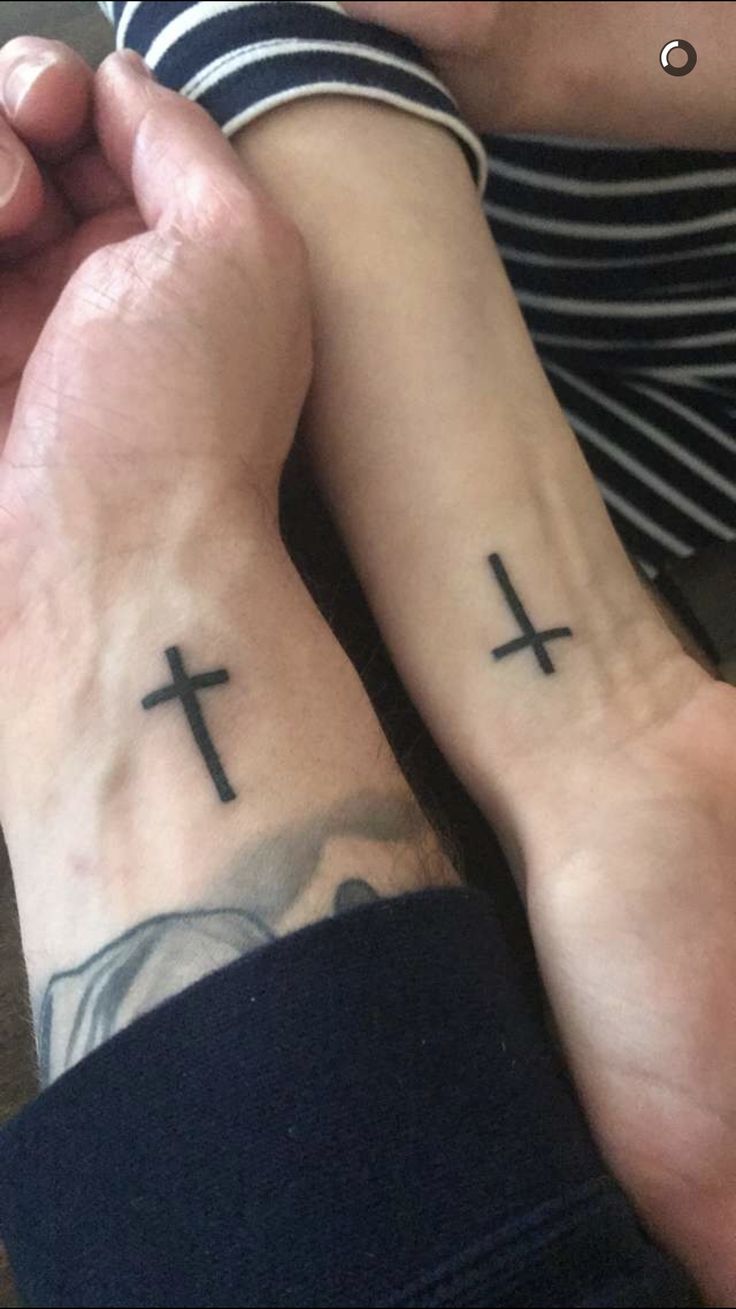 two people holding hands with cross tattoos on them