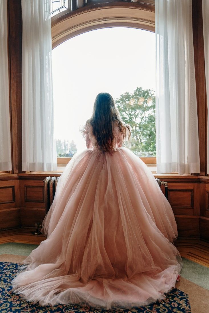 a woman in a pink dress looking out the window