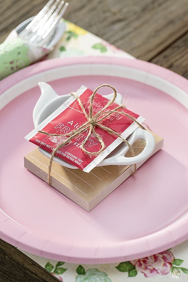 a tea bag tied with twine on top of a pink plate