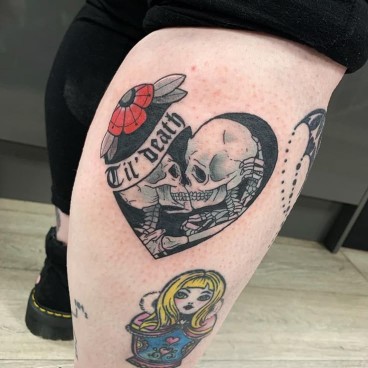 a woman's leg with tattoos on it and a skull in the shape of a heart