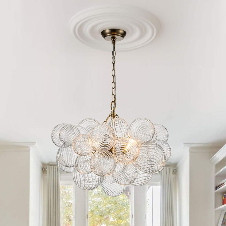 a chandelier hanging from the ceiling in a living room with white walls and windows