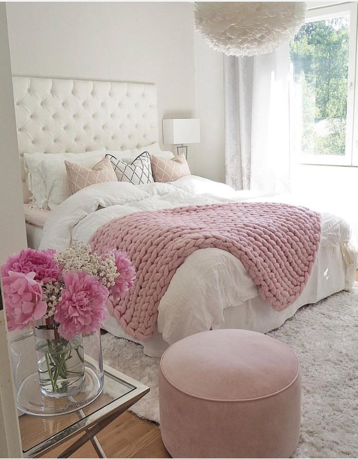 a bedroom with pink and white decor on the walls, carpeted flooring and bedding