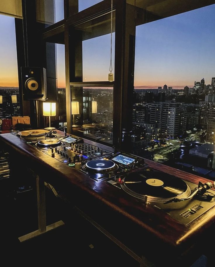 a record player sitting on top of a wooden table in front of a large window