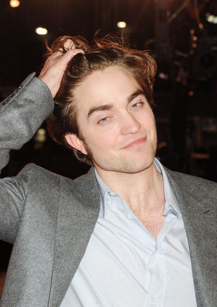 a man in a gray suit and white shirt is smiling at the camera with his hand on his head