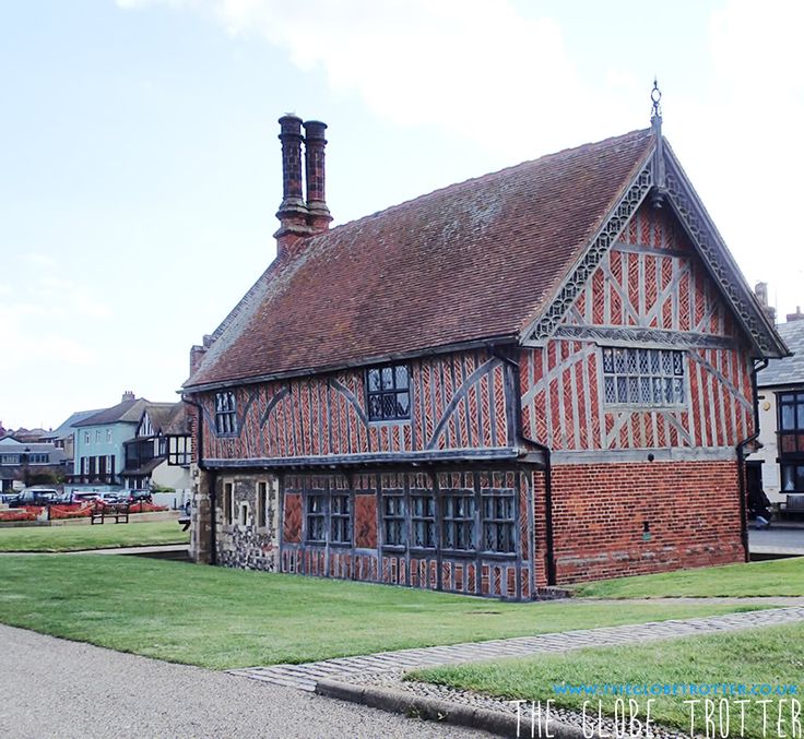 an old brick building sitting on the side of a road next to a lush green field