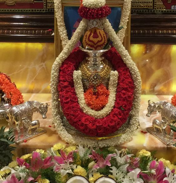 the statue is made up of red and white flowers, surrounded by silver vases