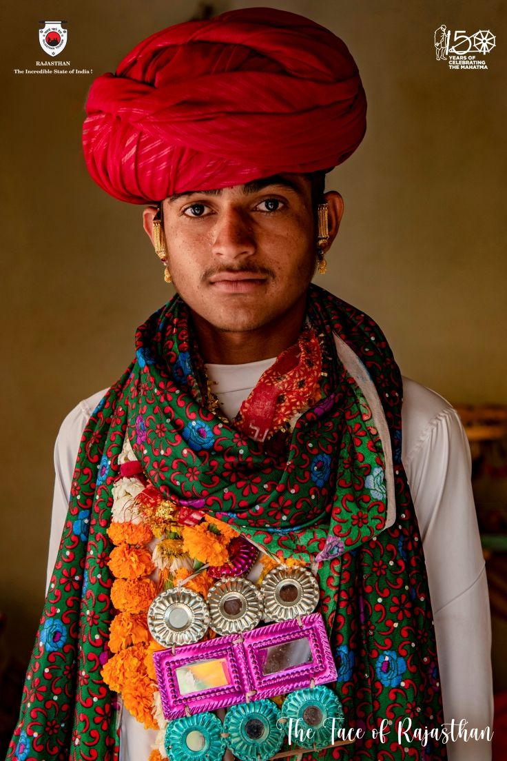 a man wearing a red turban and colorful scarf